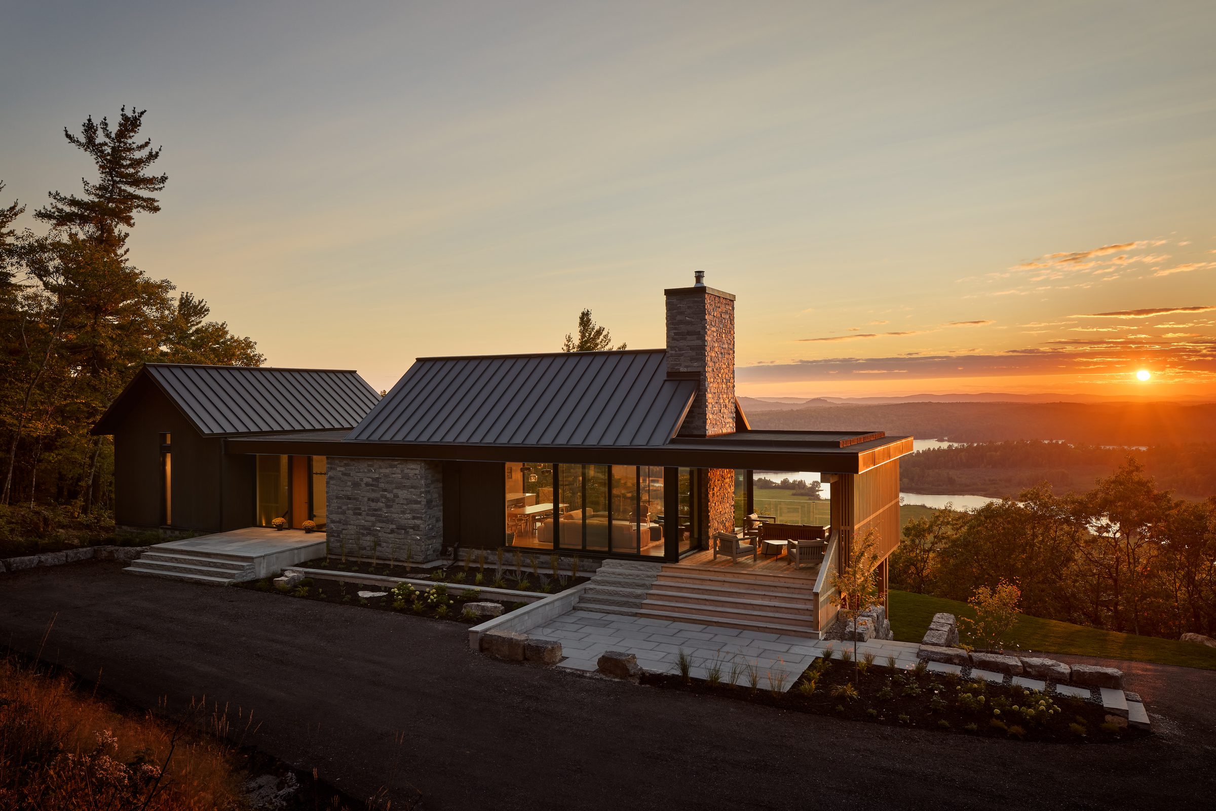 Modern hillside home at sunset with large aluminum windows overlooking a lake